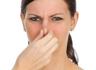 Woman holding nose because of bad smell in car